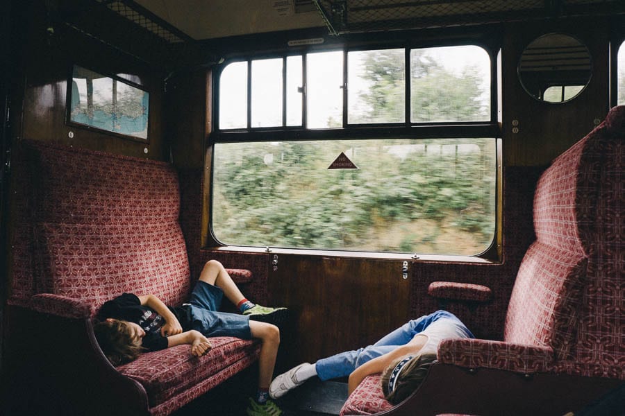 Luce and Theo lying on train seats