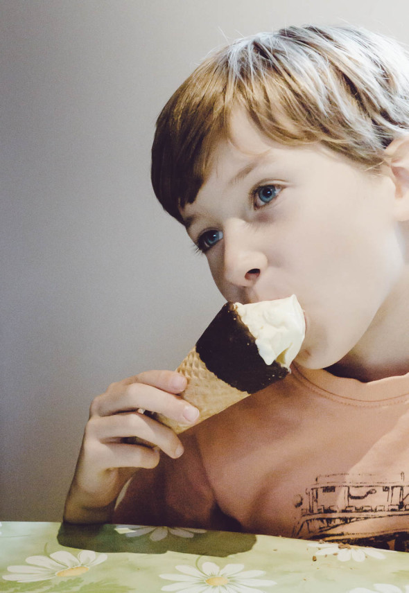Child eating cone with vanilla ice cream